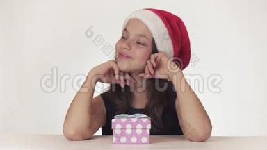 漂亮快乐的少女戴着圣诞老人的帽子梦想着礼物，在盒子里收到礼物，扔出不喜欢的礼物